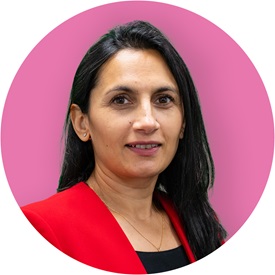 A woman in a red jacket and with black hair looks at the camera